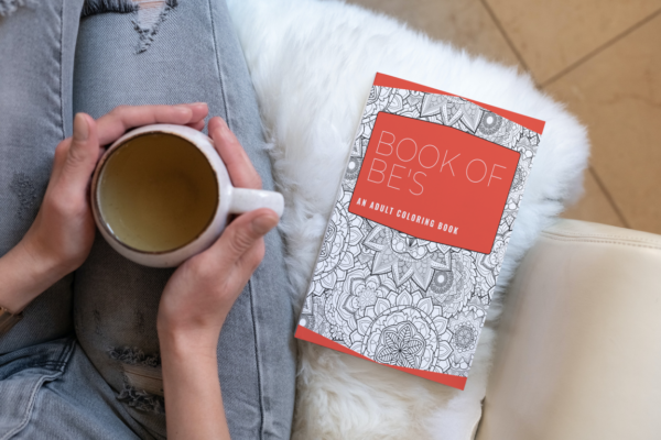 A women with coffee mug and Book of Be's sitting beside her.